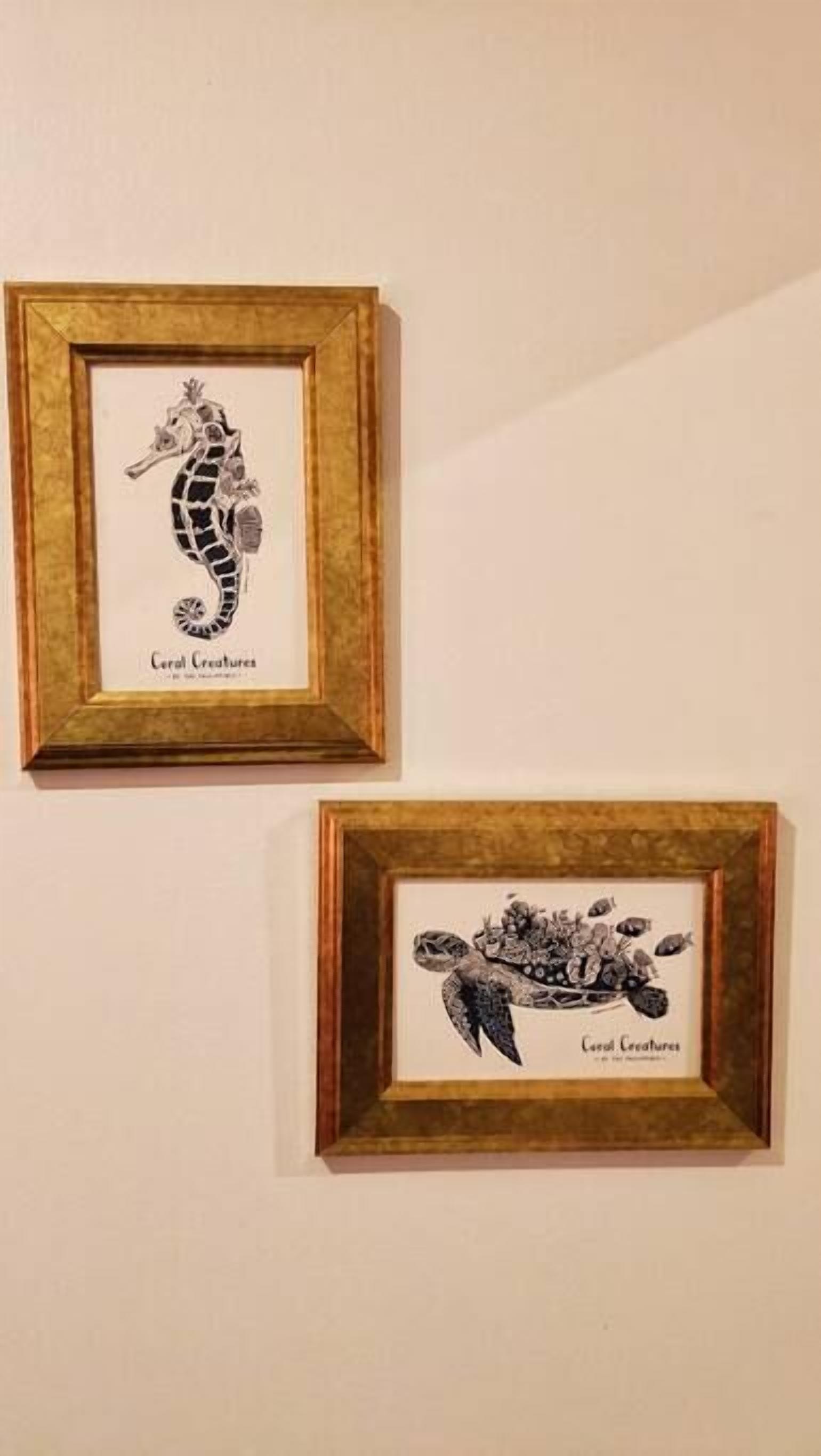 Twee kunstwerken in lijsten aan een muur.