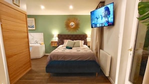 A bedroom with a bed, bedside lamps, a television, and a radiator.