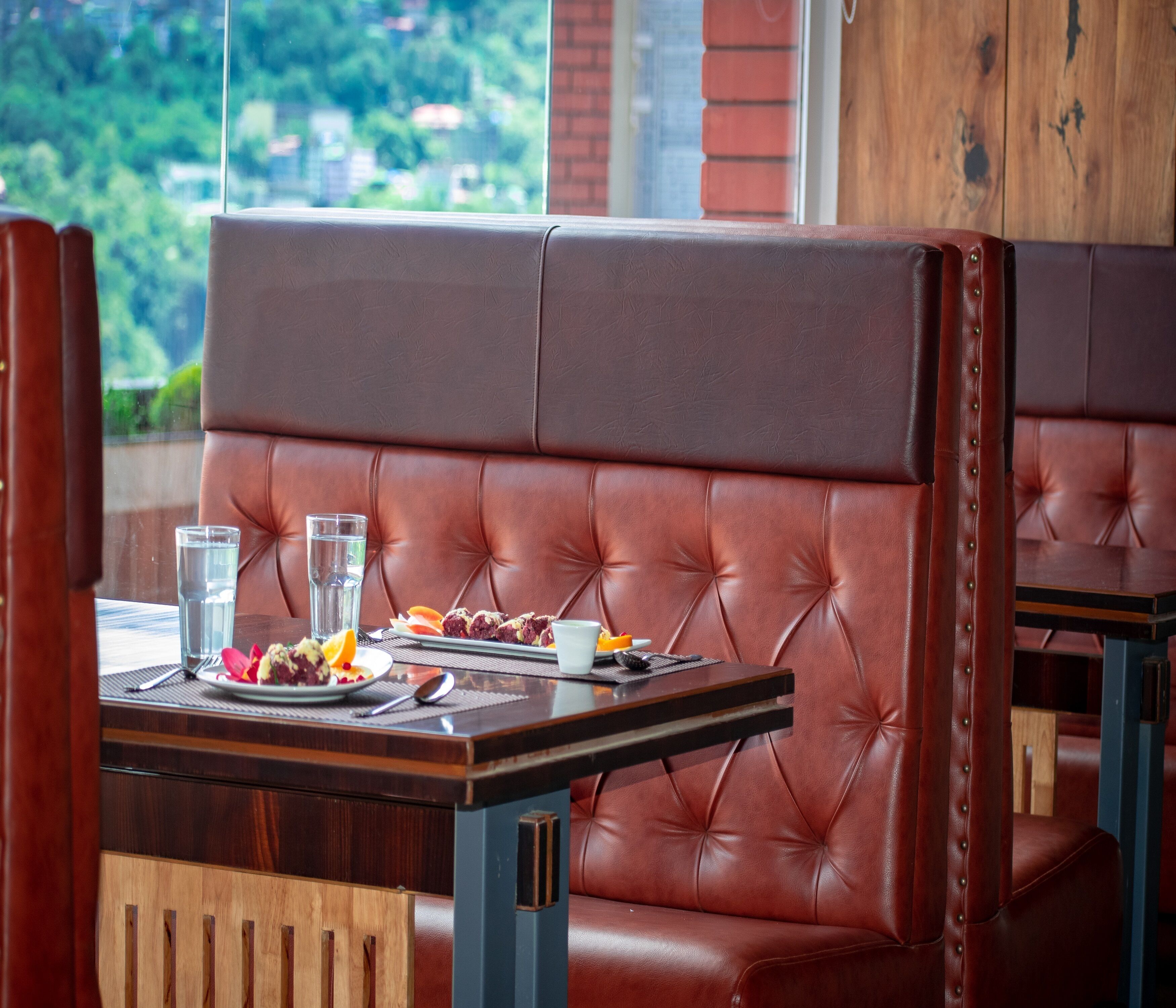 A restaurant booth with a cushioned backrest, a table with a plate of food, glasses, and cutlery.