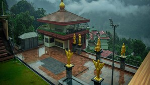 A temple with golden statues, a bell tower, and a view of mist-covered mountains. - Oro Montana Hotels and Resort (Gangtok)