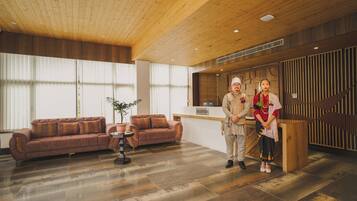 A reception area with a wooden ceiling, a reception desk, a brown sofa, and a potted plant.