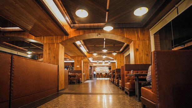 A restaurant with wooden walls and ceiling, booths, and a patterned floor. - Oro Montana Hotels and Resort (Gangtok)