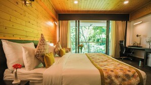 A hotel room with a large bed, a desk, and a view of trees through the window. - Oro Montana Hotels and Resort (Gangtok)