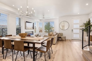 A spacious living area with a dining table, sofa, and a staircase.