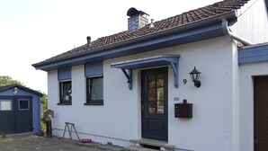 Een wit gebouw met donkerblauwe accenten, een schoorsteen en een zwarte deur.