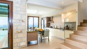 Cozinha moderna com área de refeições, escada e vista para o oceano.