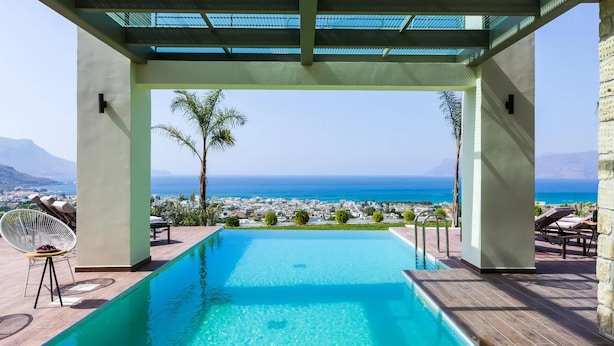 Área da piscina com vista clara para o mar e um horizonte urbano ao fundo.