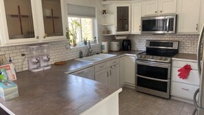 A kitchen with white cabinets, a stainless steel stove, a microwave, and a sink.