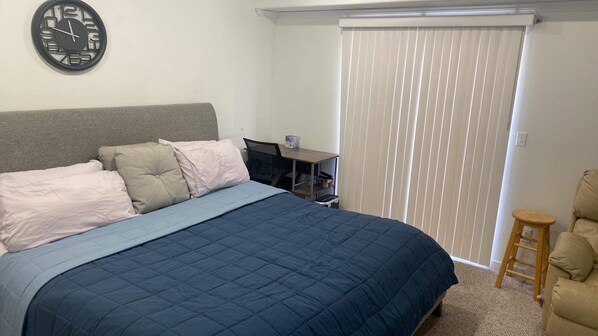 A bedroom with a bed, a desk, and a chair.