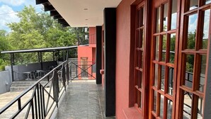A covered corridor with a tiled floor, metal railing, and large windows with a grid pattern. - Novel Enterprises Bed and Breakfast (Rustenburg)