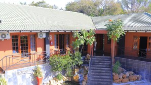 A building with a reception area, outdoor seating, and a staircase leading to an upper level. - Novel Enterprises Bed and Breakfast (Rustenburg)
