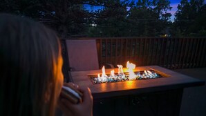 Una persona sentada en una terraza de madera con una chimenea frente a ella.