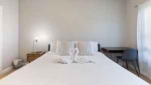 A hotel room with a neatly made bed, a desk, a chair, and a lamp. - Stylish Golf  Beach Getaway (Myrtle Beach)