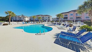 A swimming pool with lounge chairs and a white fence. - Stylish Golf  Beach Getaway (Myrtle Beach)
