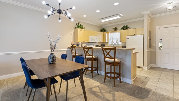 A modern kitchen with a central island, wooden chairs, and a dining table. - Stylish Golf  Beach Getaway (Myrtle Beach)