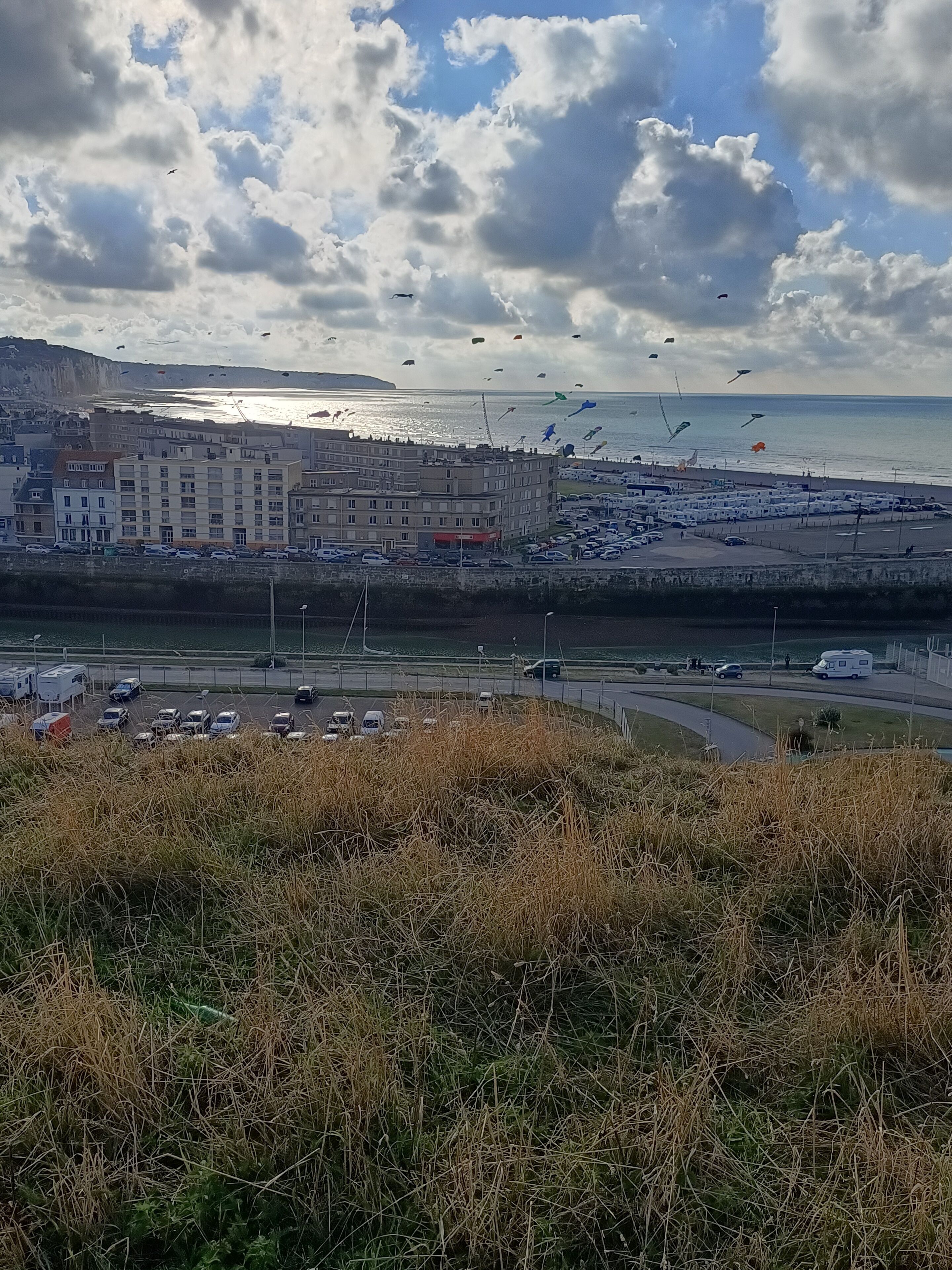 Eine Küstenstadt mit Parkplatz, Gebäuden und einem Strand im Hintergrund.