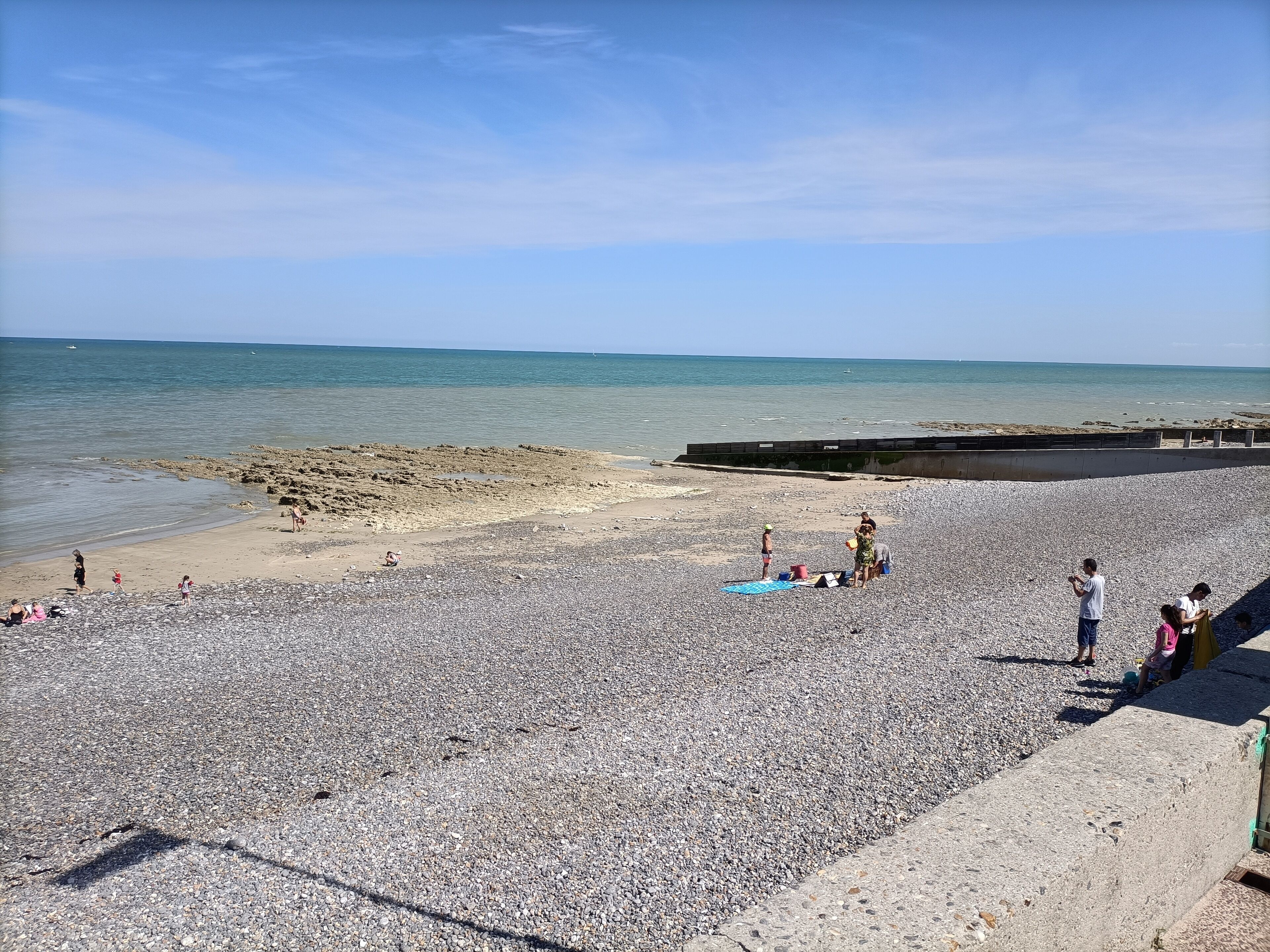 A pebbled beach with a rocky shoreline and a calm sea.