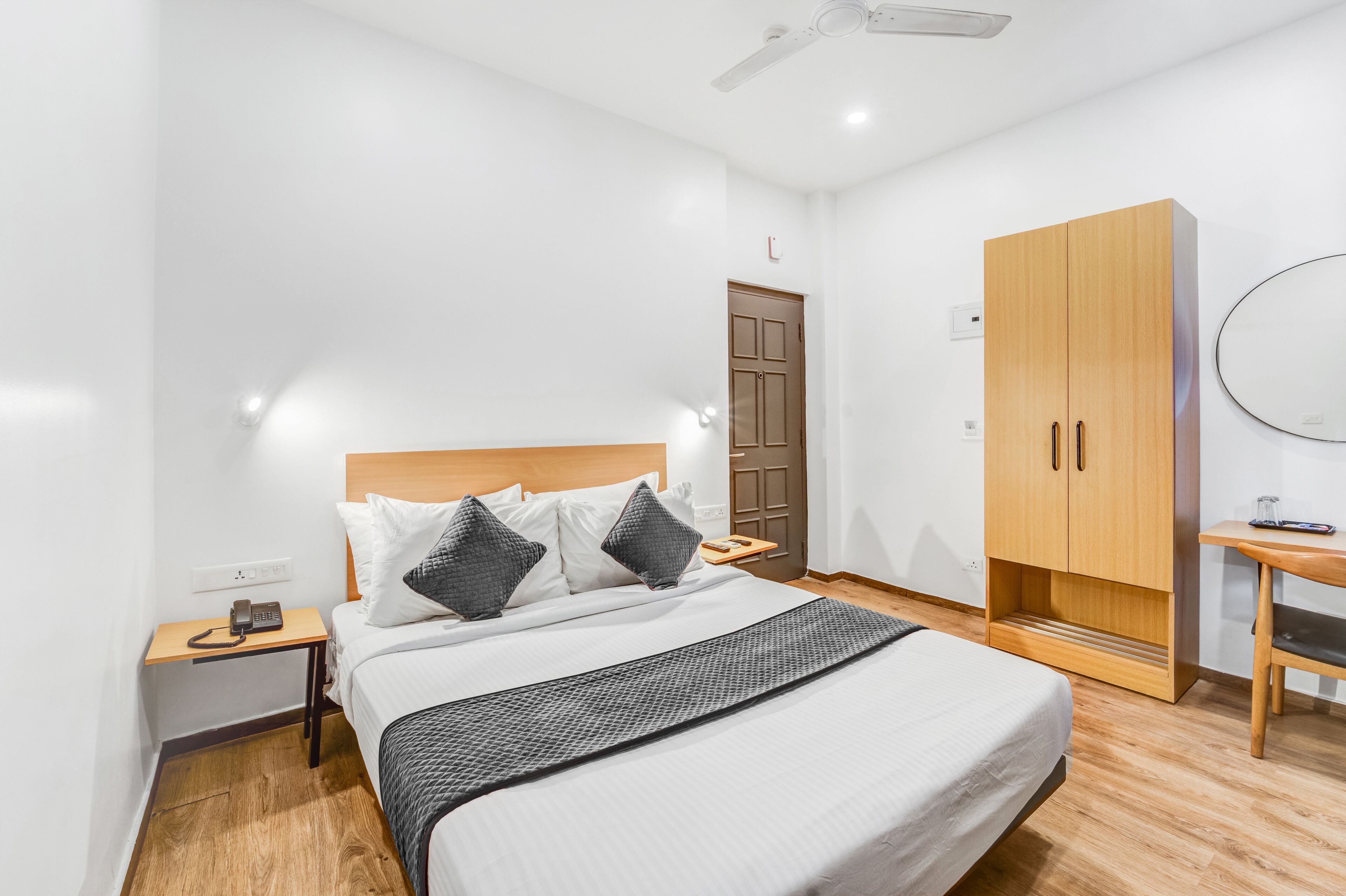 Un dormitorio ordenado con cama, mesita de noche, armario y ventilador de techo.