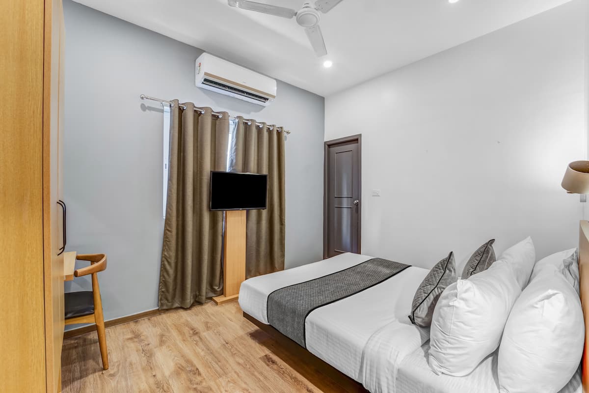 Une chambre d’hôtel équipée d’un lit, d’un bureau, d’une chaise, d’une télévision, d’un climatiseur et d’une porte.