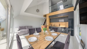A modern kitchen with a wooden countertop, a built-in oven, and a black refrigerator.
