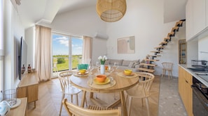 A dining area with a round table, chairs, and a view of the outdoors. - Apartamenty Sun & Snow Osada Cetniewo (Wladyslawowo)
