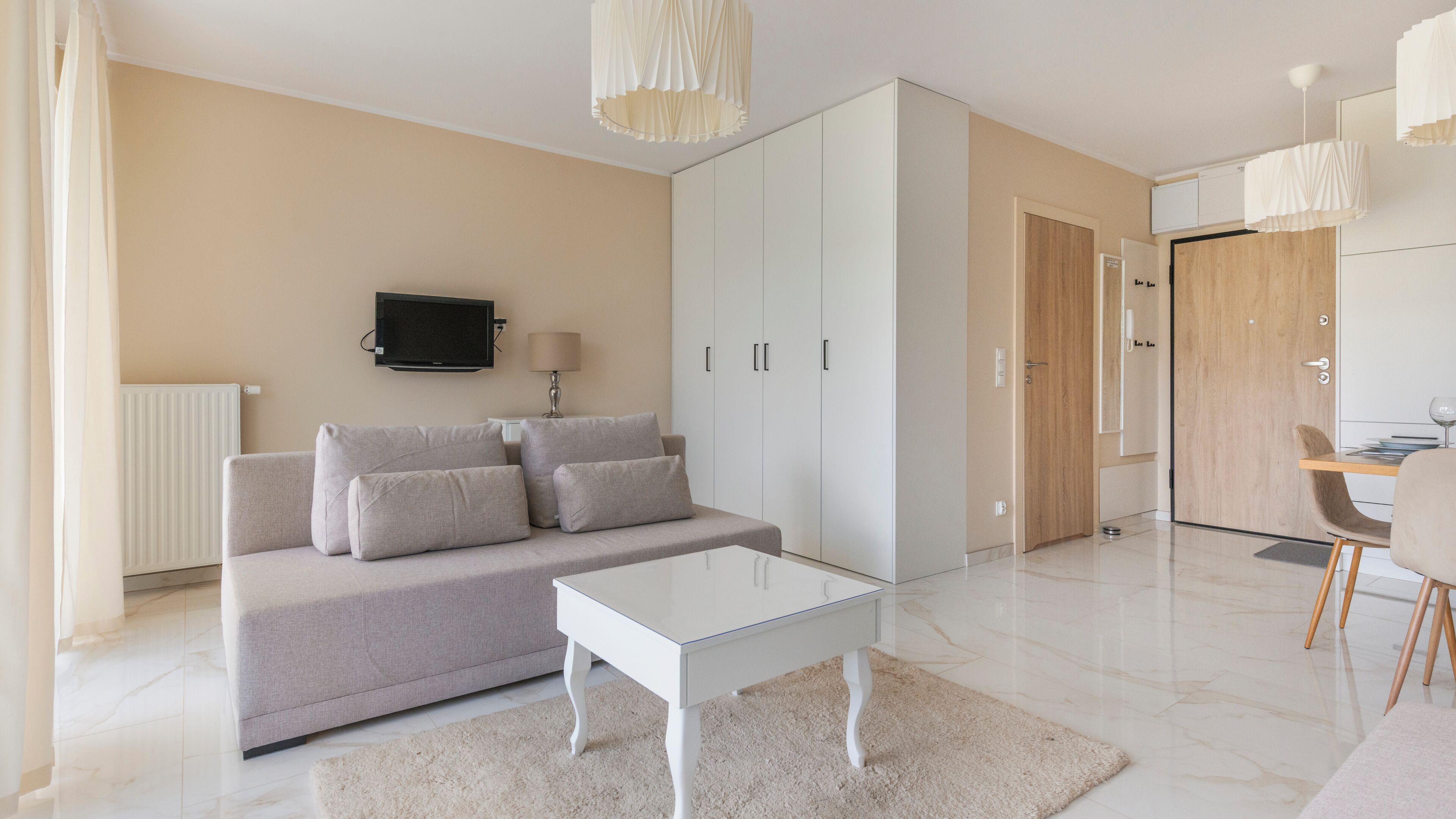 Een moderne woonkamer met een bank, salontafel, televisie en inloopkast.