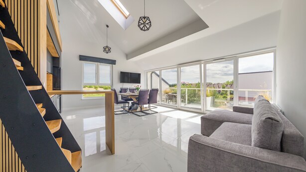 A spacious living area with a modern staircase, a dining area with a view, and a balcony with a scenic view.