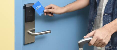Una persona utilizando un lector de tarjetas para acceder a una puerta con picaporte metálico.