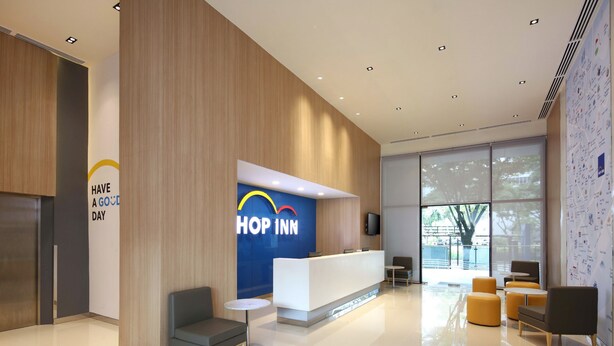 Um hall de hotel moderno com balcão de recepção, área de estar e grandes janelas.