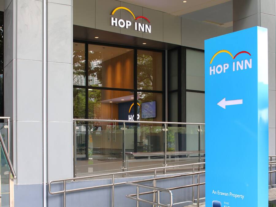 A modern building with a glass facade, a sign reading "HOP INN," and a directional arrow on a blue sign.