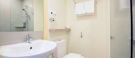 A bathroom with a white sink, toilet, and glass shower enclosure.