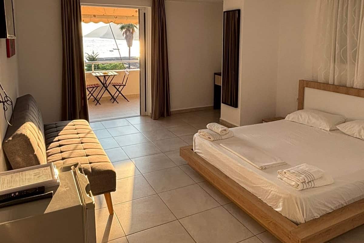A hotel room with a bed, a sofa, a desk, and a view of the outdoors.