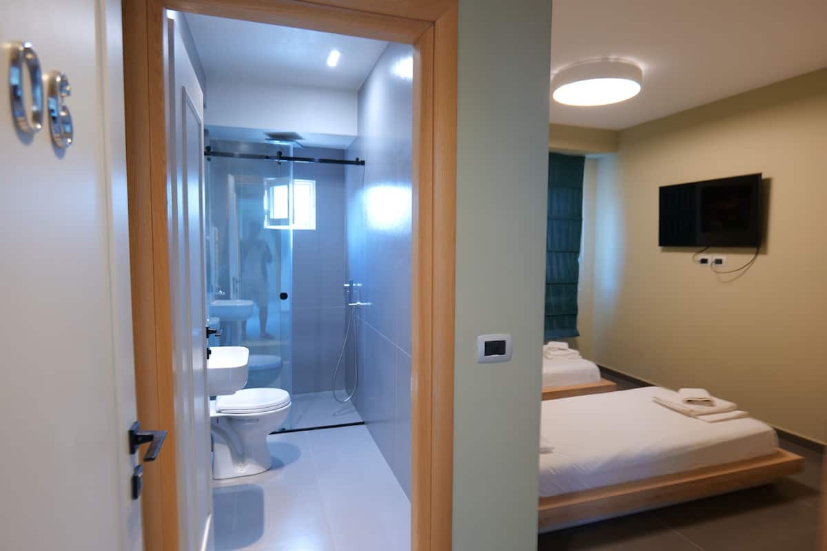 A modern bathroom with a glass shower enclosure, a toilet, and a sink.