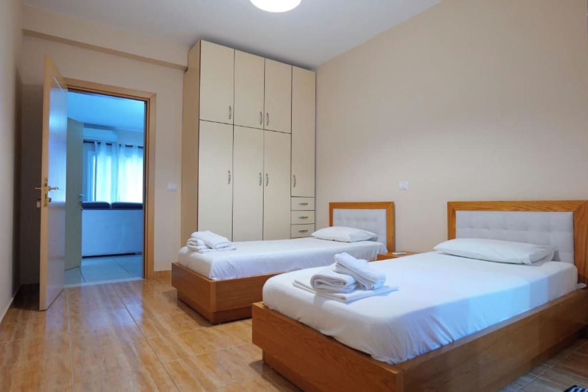 Une chambre d’hôtel avec deux lits, une armoire et une salle de bain visible à travers une porte ouverte.