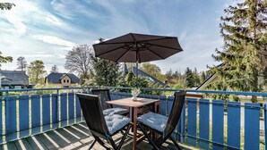 A wooden deck with a table and chairs, a large umbrella, and a blue fence. - Quietly situated apartment for up to 2 p. + infant, sauna, WLAN, balcony, bicycle shed (Prerow)