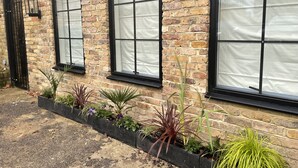 A brick building with large windows and a black metal gate. - Nestled in a grand private estate, near woodlands, easy access London (Kingston upon Thames)