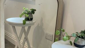 A room with two white tables, each with a potted plant. The floor is wooden, and there's a mirror on the wall. - Nestled in a grand private estate, near woodlands, easy access London (Kingston upon Thames)