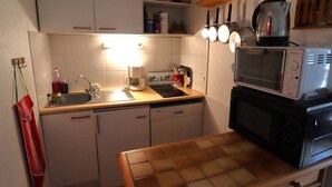 A compact kitchen with white cabinets, a microwave, a coffee maker, and a sink. - Cozy apartment 3-5 pers, pool, near slopes, village center (Arêches-Beaufort)