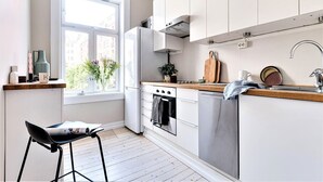 Une cuisine moderne avec des armoires blanches, un réfrigérateur en acier inoxydable, un four et un évier.