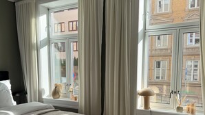 Une chambre à coucher avec un lit, une chaise, un tapis et une fenêtre avec des rideaux.