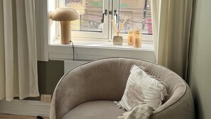 Une pièce avec une fenêtre, une chaise et une lampe.