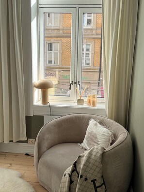 Une pièce avec une fenêtre, une chaise et une lampe.