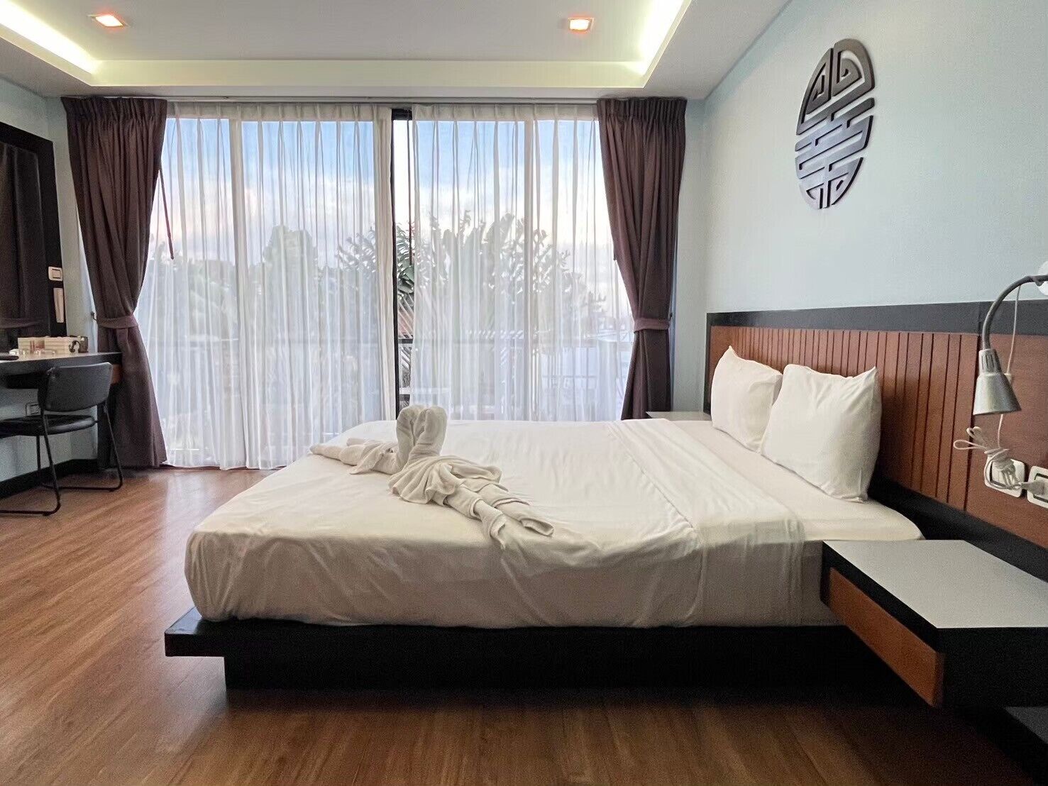 A modern hotel room with a large bed, a desk, and a chair.