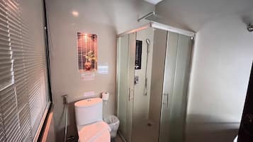 Une salle de bain comprenant des toilettes, un bidet et une cabine de douche en verre.