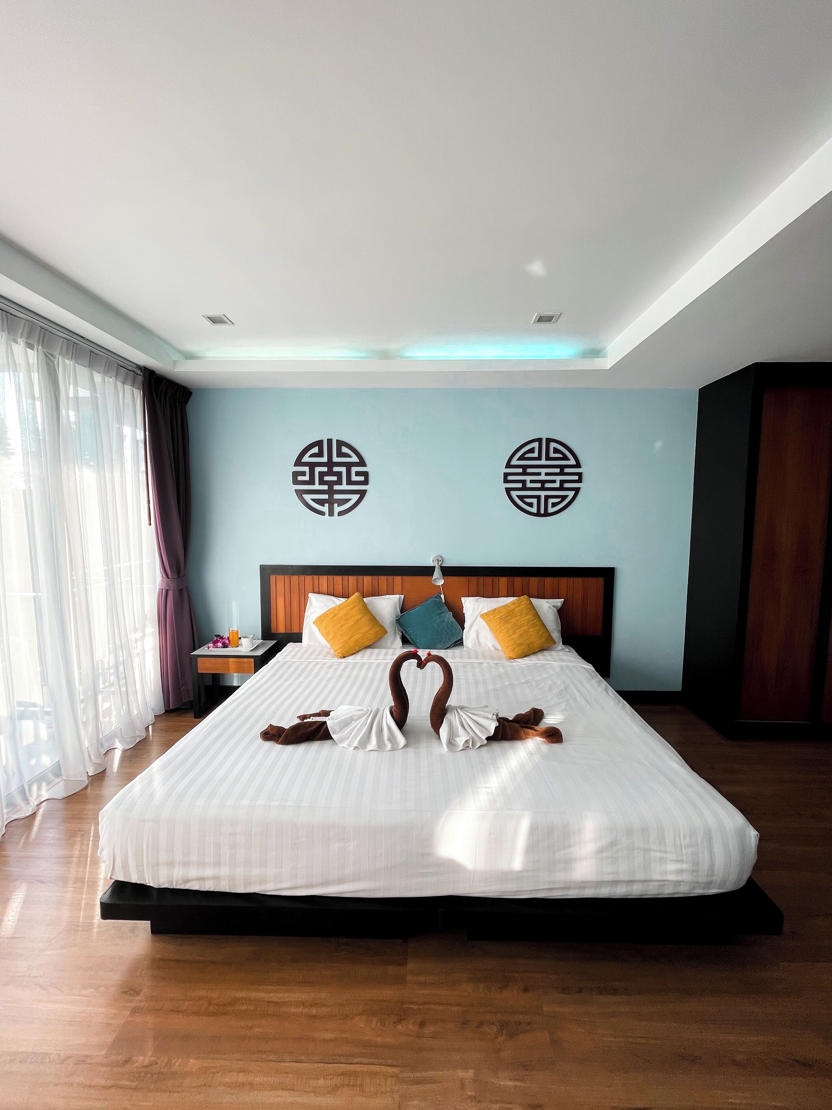 Habitación de hotel con una cama grande, una mesita de noche, un escritorio y una ventana con cortinas.