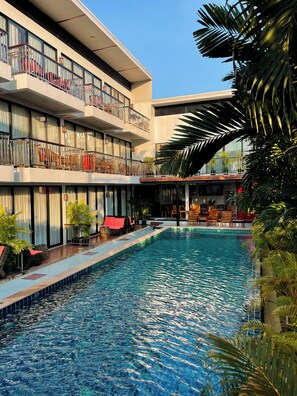 Un hôtel doté d’une piscine, de plusieurs balcons et de plantes d’intérieur.
