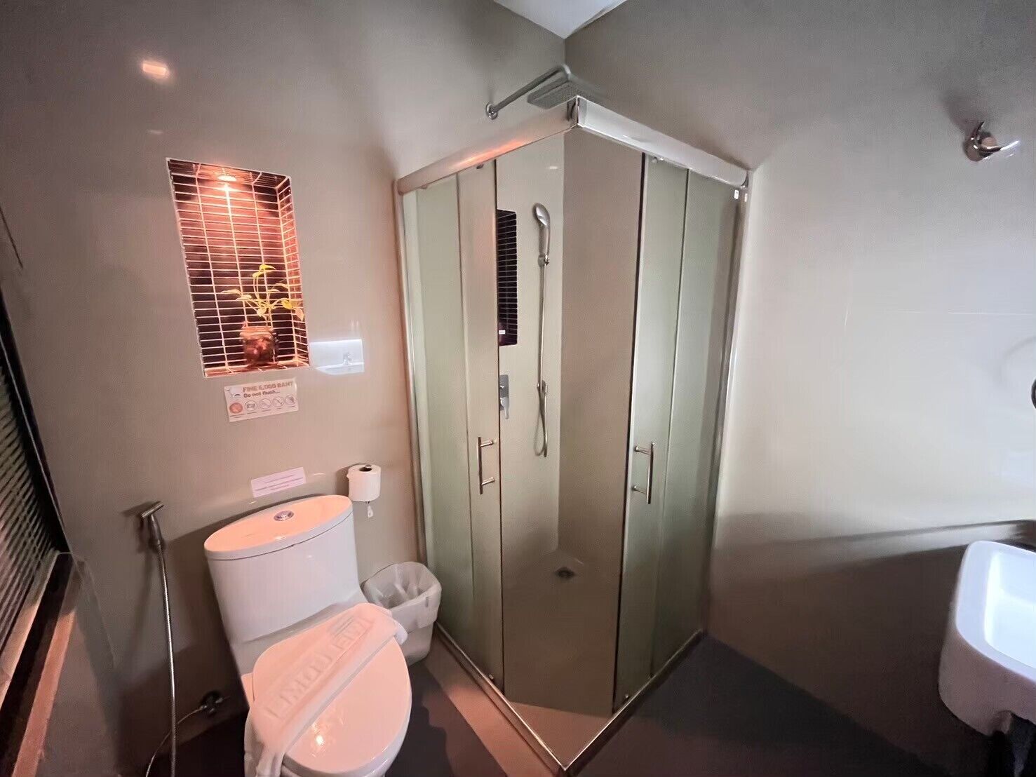 A bathroom with a toilet, a glass-enclosed shower, and a sink.