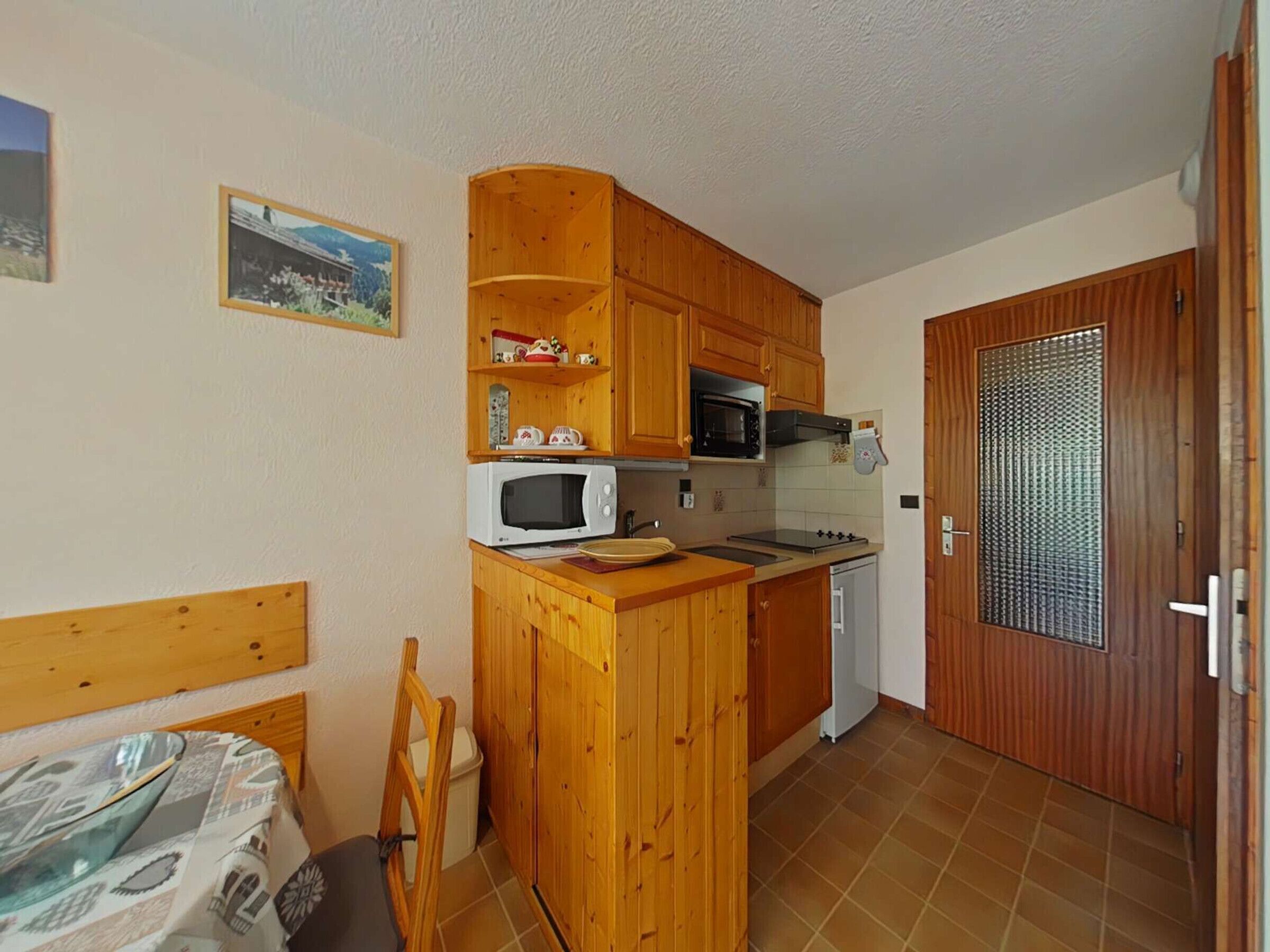 Una cocina compacta con armarios de madera, un microondas, una estufa y un lavamanos pequeño.