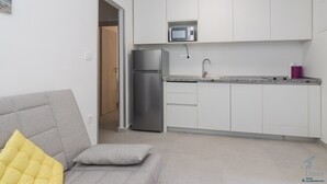 Una cocina moderna con armarios blancos, un refrigerador de acero inoxidable y un microondas.
