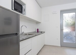 Une cuisine moderne équipée d’un réfrigérateur en acier inoxydable, d’un four à micro-ondes et d’un plan de travail en granit.